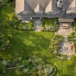 Aerial view of a lush New England estate landscape with layered planting, stone terraces, and timeless outdoor structure.