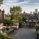 An elegant Boston rooftop terrace featuring layered gardens, comfortable lounge and dining areas, and sweeping views across the city.
