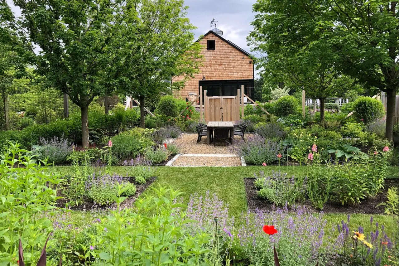 A garden setting with native plantings surrounding a simple barn structure, creating a functional outdoor space that blends naturally with its surroundings.