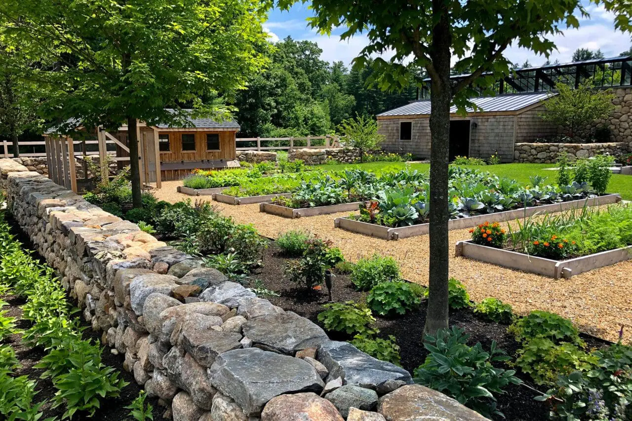 A sustainable garden with raised vegetable beds, native plantings, and stone walls that blend function, beauty, and natural materials.