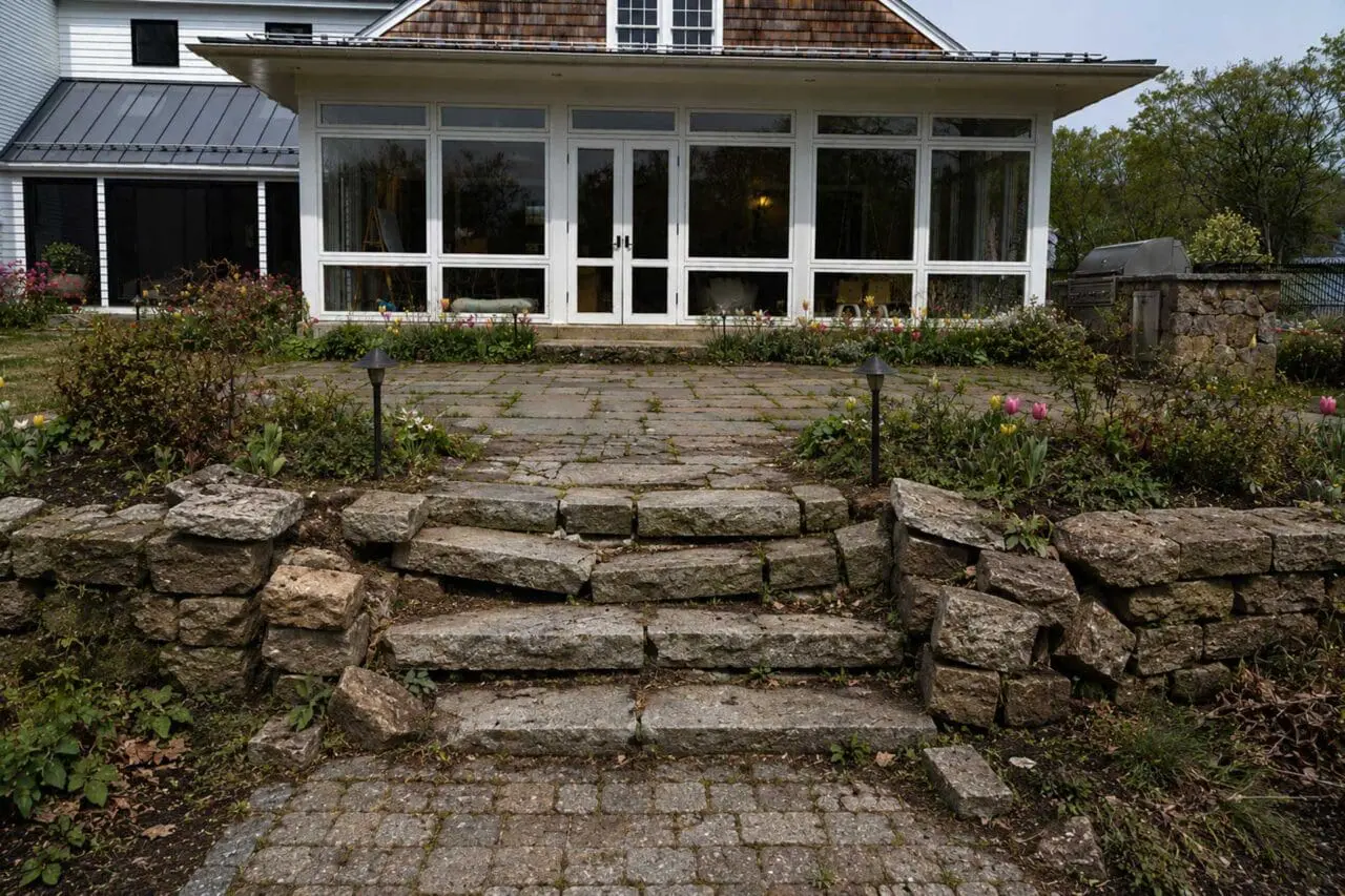 Uneven stone steps, settling walls, and shifting pavers can signal deeper issues with base preparation, drainage, tree roots, or age before a landscape project begins.