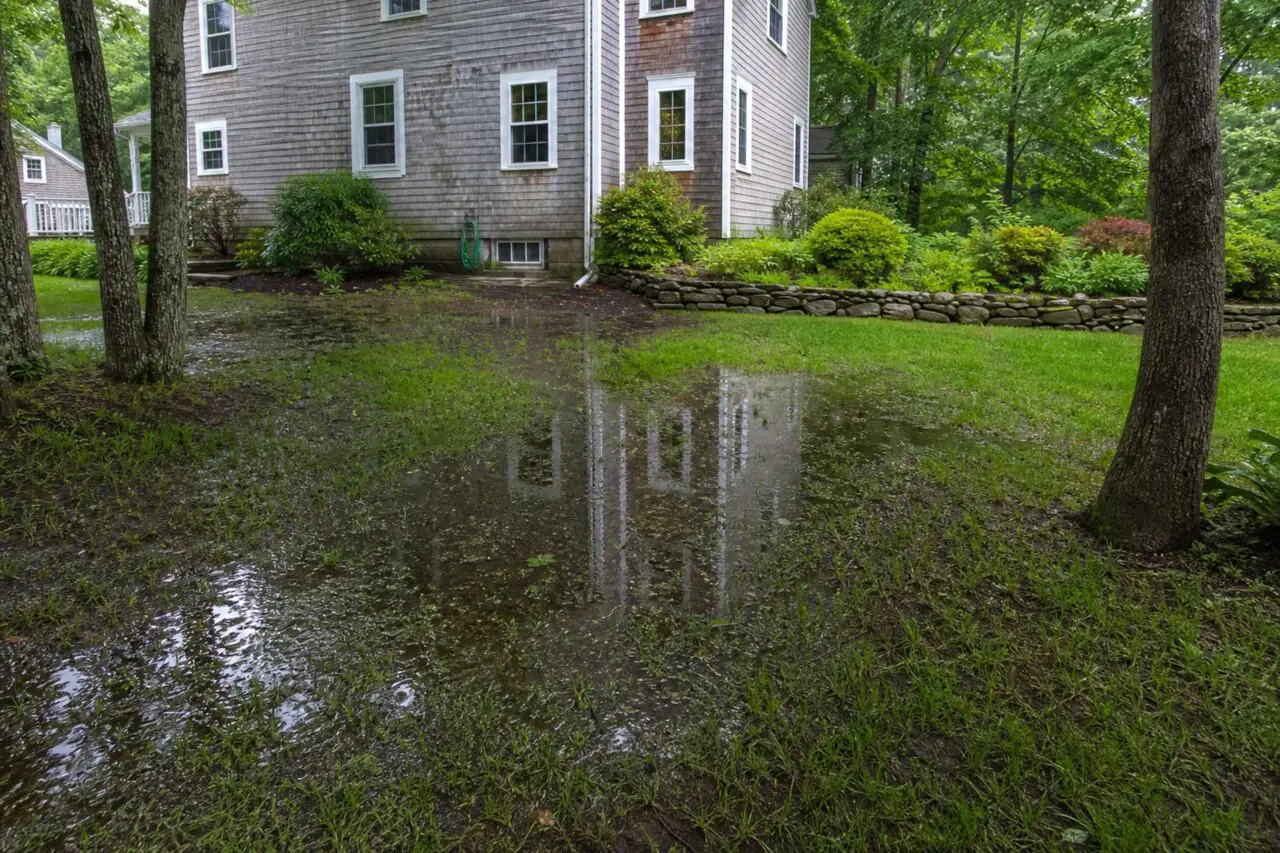 Standing water spreads across a low section of this Sudbury backyard after heavy rain.