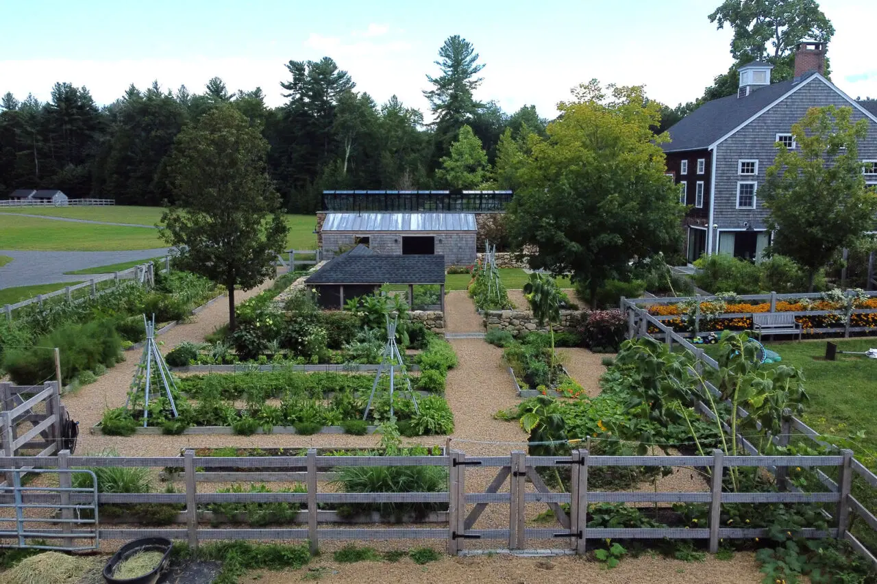 An overhead view reveals the geometric layout of raised beds and stone walls within the productive garden.
