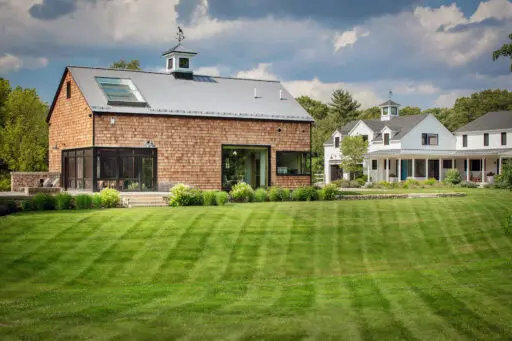 A strong lawn axis visually connects barn and farmhouse, unifying the estate through alignment and proportion. Photo: Michael J. Lee