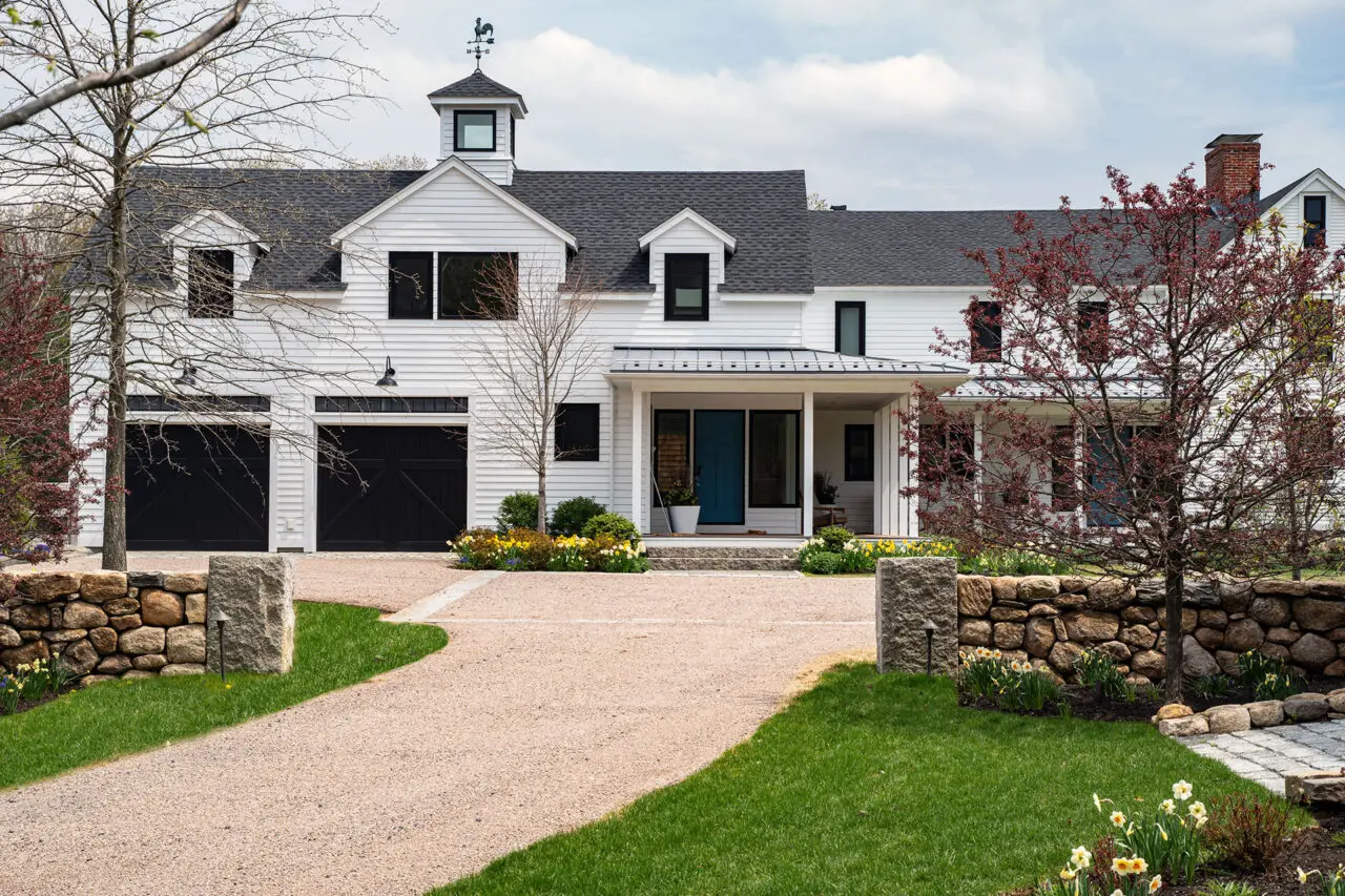 A gravel drive court is framed by stone walls, balancing function, durability, and formal estate character.