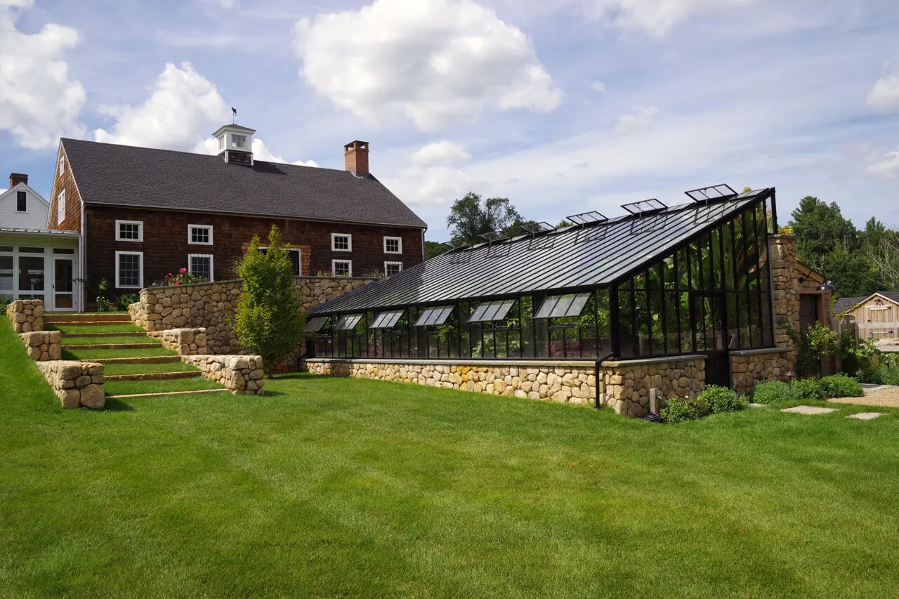 Stone steps link the farmhouse to the greenhouse, emphasizing daily movement between living and growing spaces.
