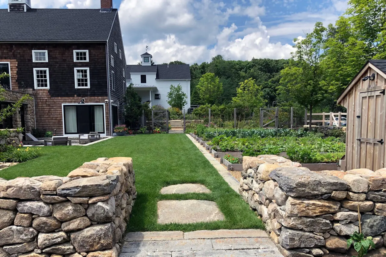 A stone garden entry aligns with the lawn axis, creating clear sightlines and a strong sense of arrival.