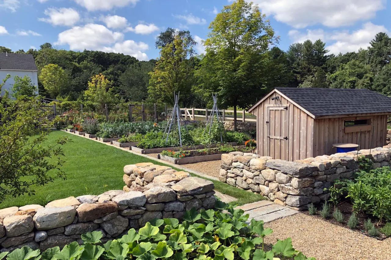 A simple garden shed anchors the kitchen garden, providing storage while reinforcing the estate’s working landscape aesthetic.