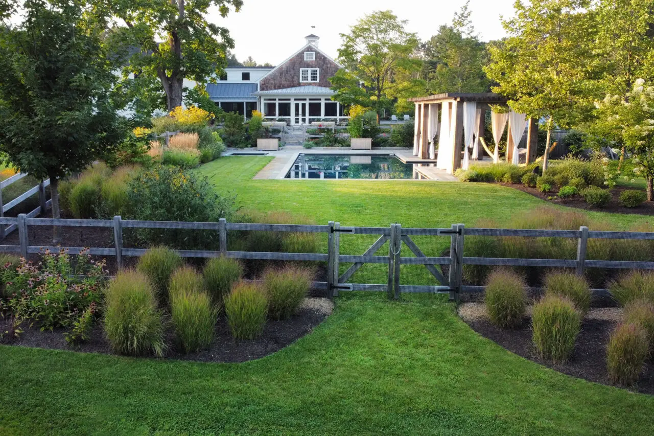 Subtle fencing and ornamental plantings define the pool area while preserving open views and maintaining estate-scale cohesion.