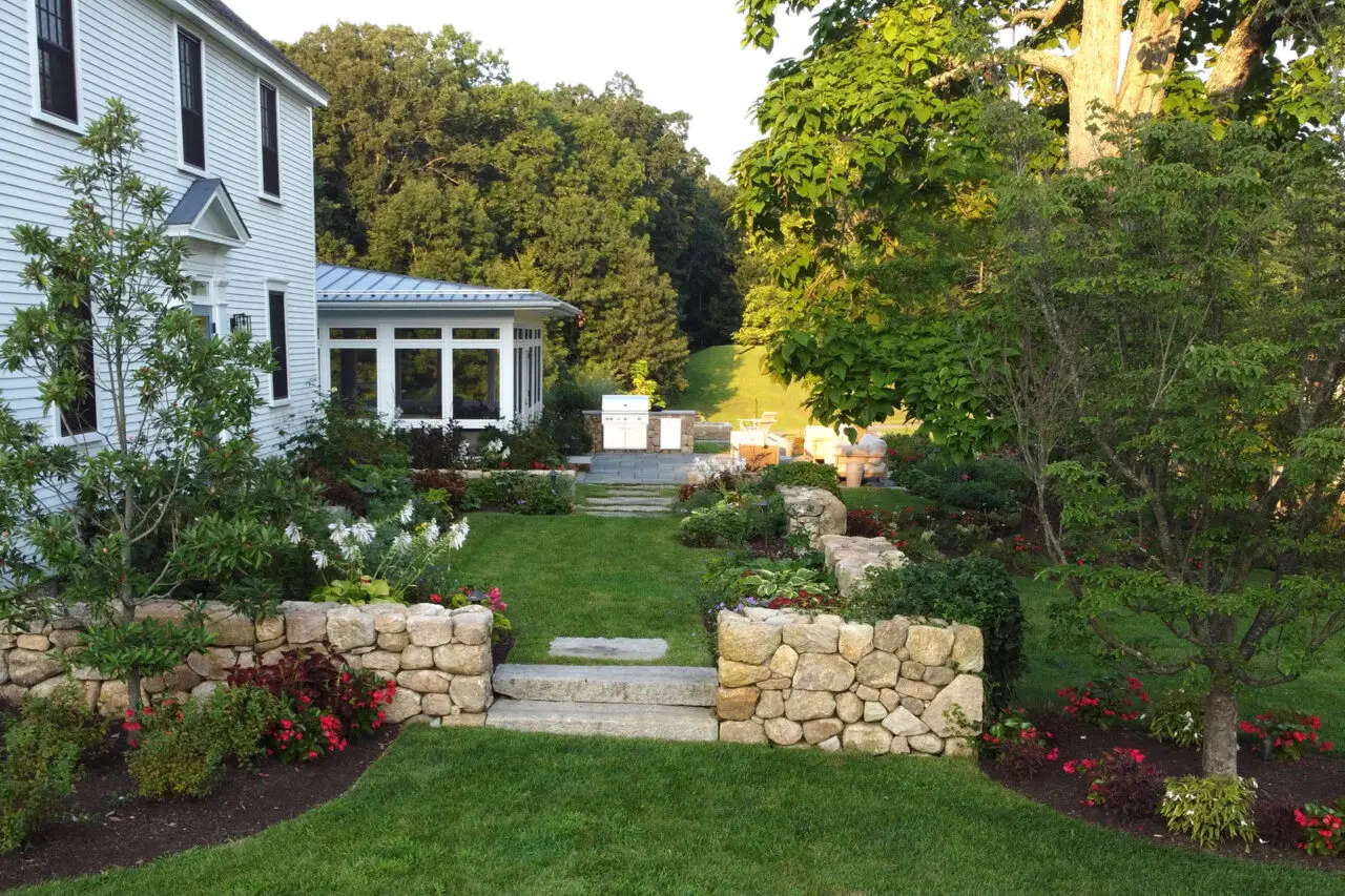 Stone steps connect a screened porch to the garden terrace, extending living space while maintaining a seamless indoor-outdoor relationship.