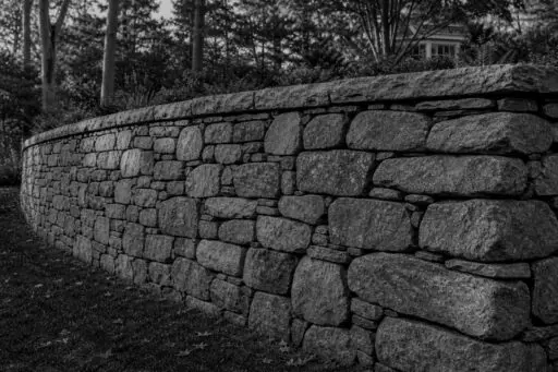 Acton, MA - A stone retaining wall leans outward, indicating movement and possible structural failure.