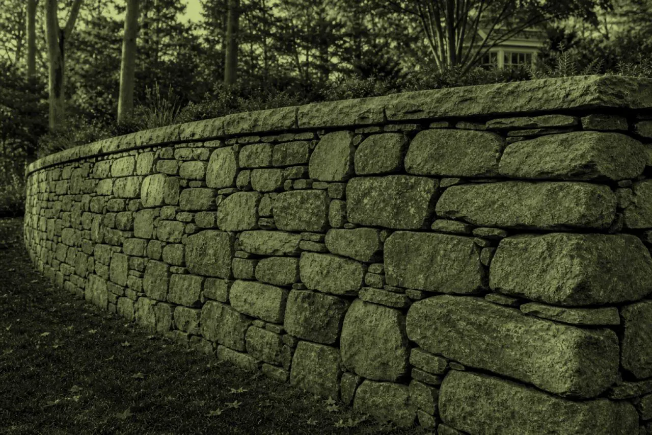 Acton, MA - A stone retaining wall leans outward, indicating movement and possible structural failure.