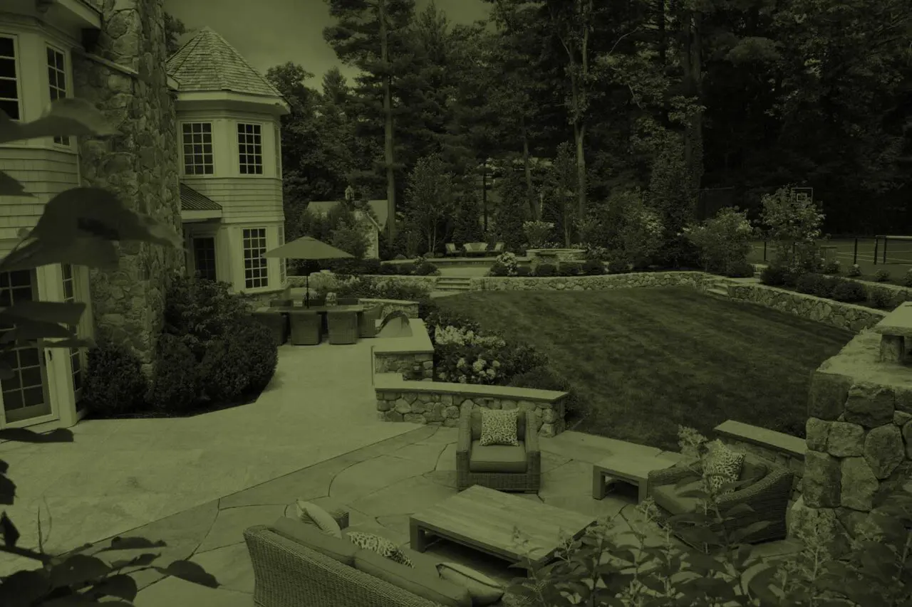 Wellesley, MA - A thoughtfully designed landscape with stone terraces, lawn, layered plantings, and inviting outdoor living spaces.