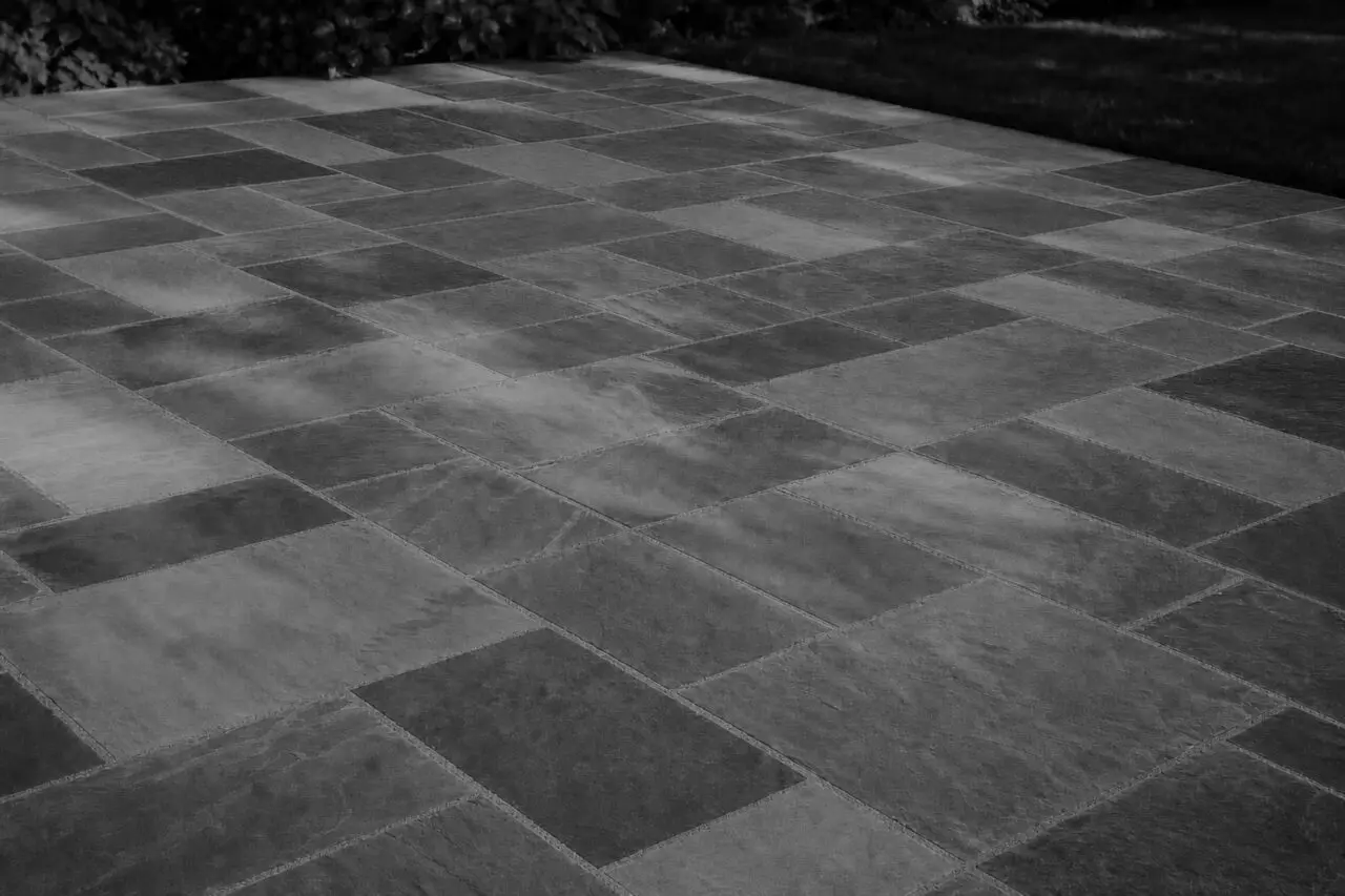 Belmont, MA - This dry-laid bluestone patio shows how frost heave, poor drainage, or an unstable base can cause individual stones to lift, sink, or rock after winter.