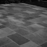 Belmont, MA - This dry-laid bluestone patio shows how frost heave, poor drainage, or an unstable base can cause individual stones to lift, sink, or rock after winter.