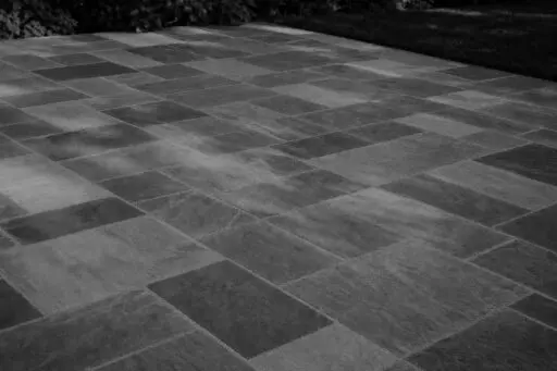 Belmont, MA - This dry-laid bluestone patio shows how frost heave, poor drainage, or an unstable base can cause individual stones to lift, sink, or rock after winter.