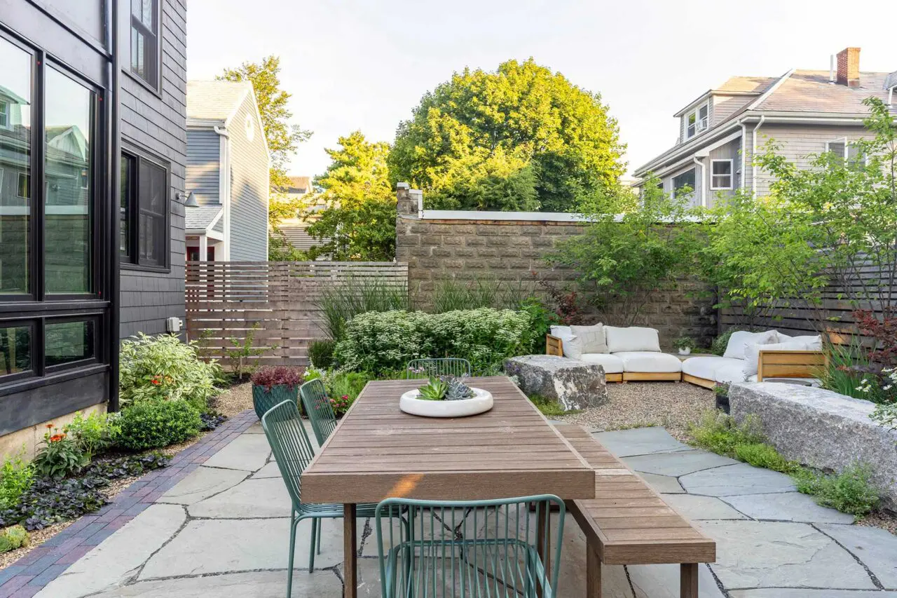 The dining terrace is positioned to connect directly to the home, with bluestone paving and layered plantings creating a cohesive and usable outdoor room.