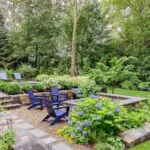 This gravel fire pit terrace is softened by hydrangeas and layered planting, offering a relaxed gathering space set slightly apart from the pool. photo credit: Michael J Lee