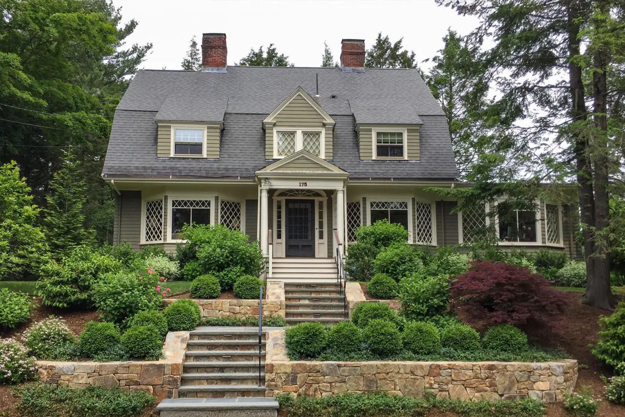 Granite steps, fieldstone walls, and layered planting give this Newton front terrace a more structured, welcoming arrival while preserving a natural New England feel.