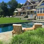Duxbury, MA - A backyard retreat complete with an in ground pool, lush lawn and plantings, bluestone surfaces, and a built in kitchen.