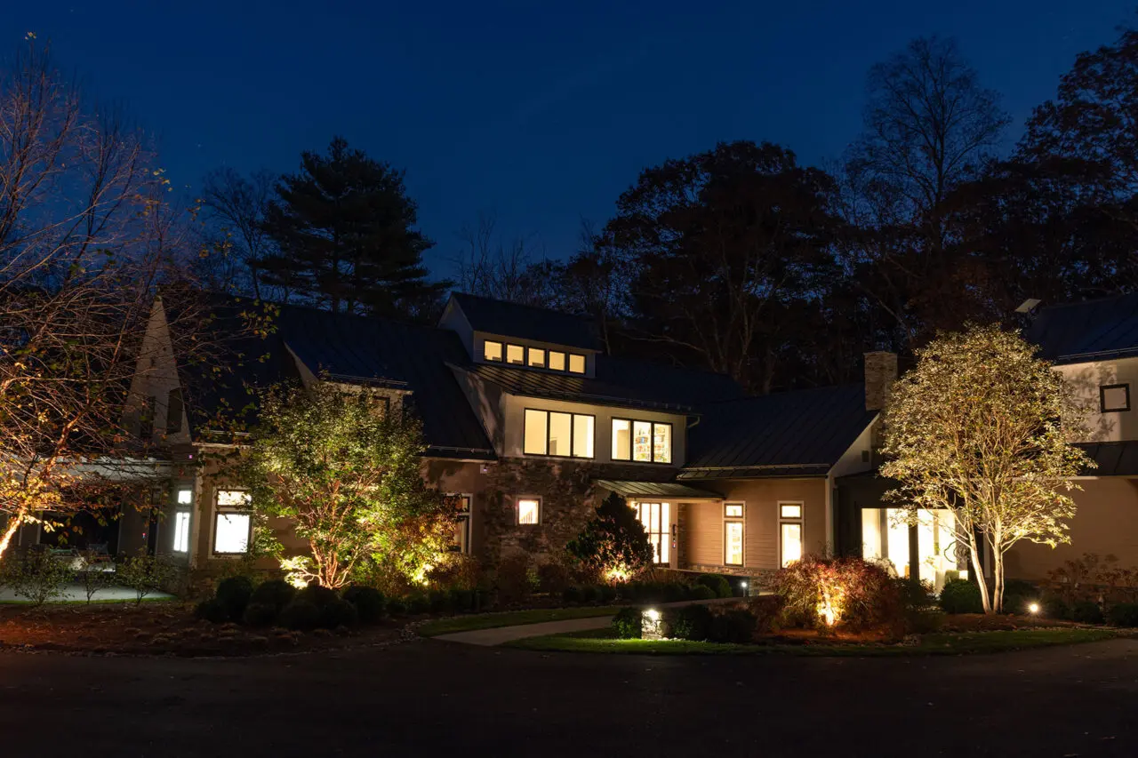 Lawn lighting highlights trees and open space, extending visual interest across the property after dark.