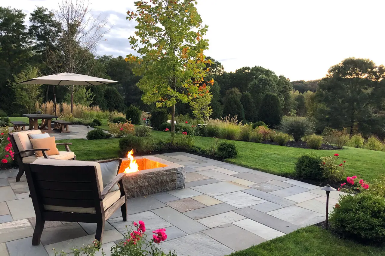 A granite fire pit set within a bluestone patio in Wayland, MA offers long-term durability and a welcoming focal point that supports casual gatherings and seasonal use.