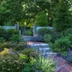 This Lincoln garden pairs lush planting beds with natural stone edging for a refined, well-structured New England landscape.