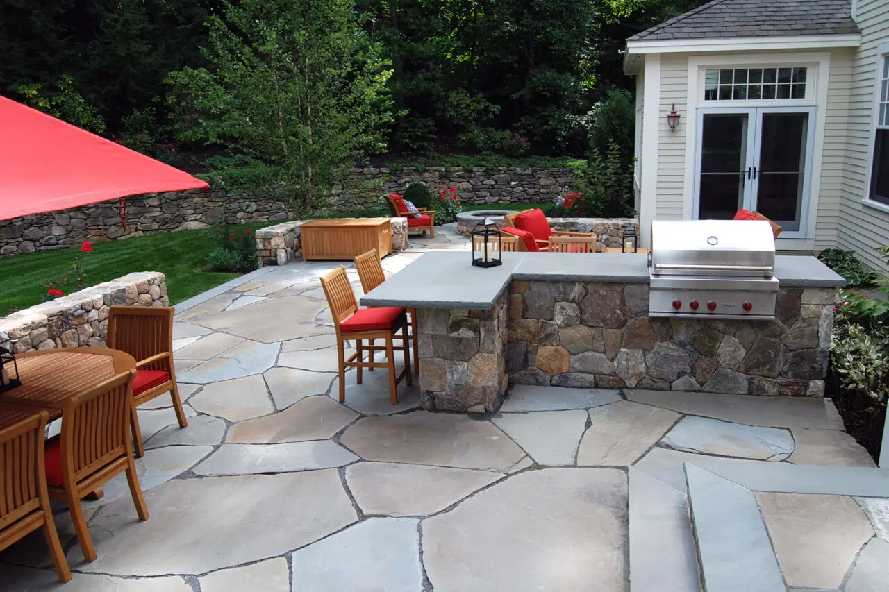 Outdoor dining space with a stone patio and built-in grill, combining durable materials with a comfortable layout for everyday cooking and entertaining.