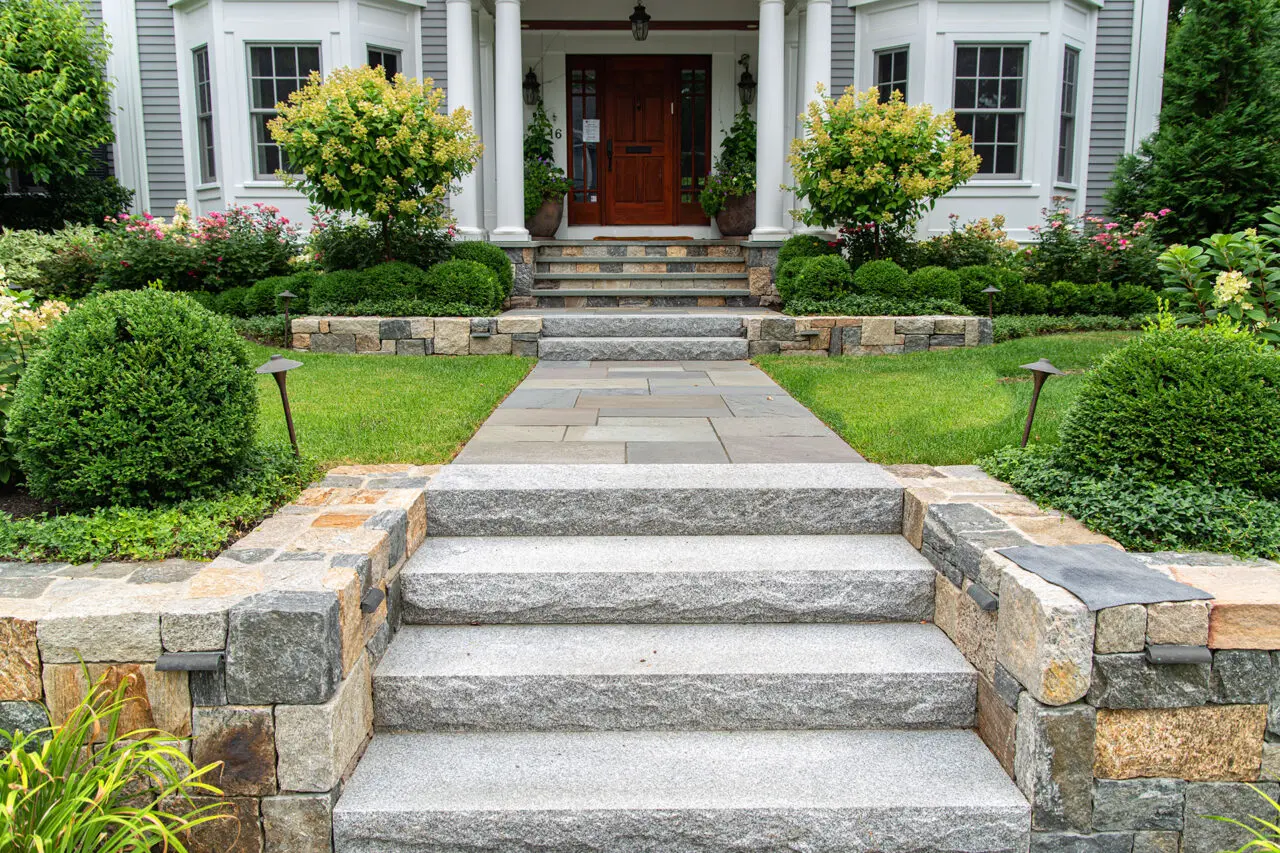Formal granite steps and cut stone walls define a stately, symmetrical entry suited to Wellesley estates.