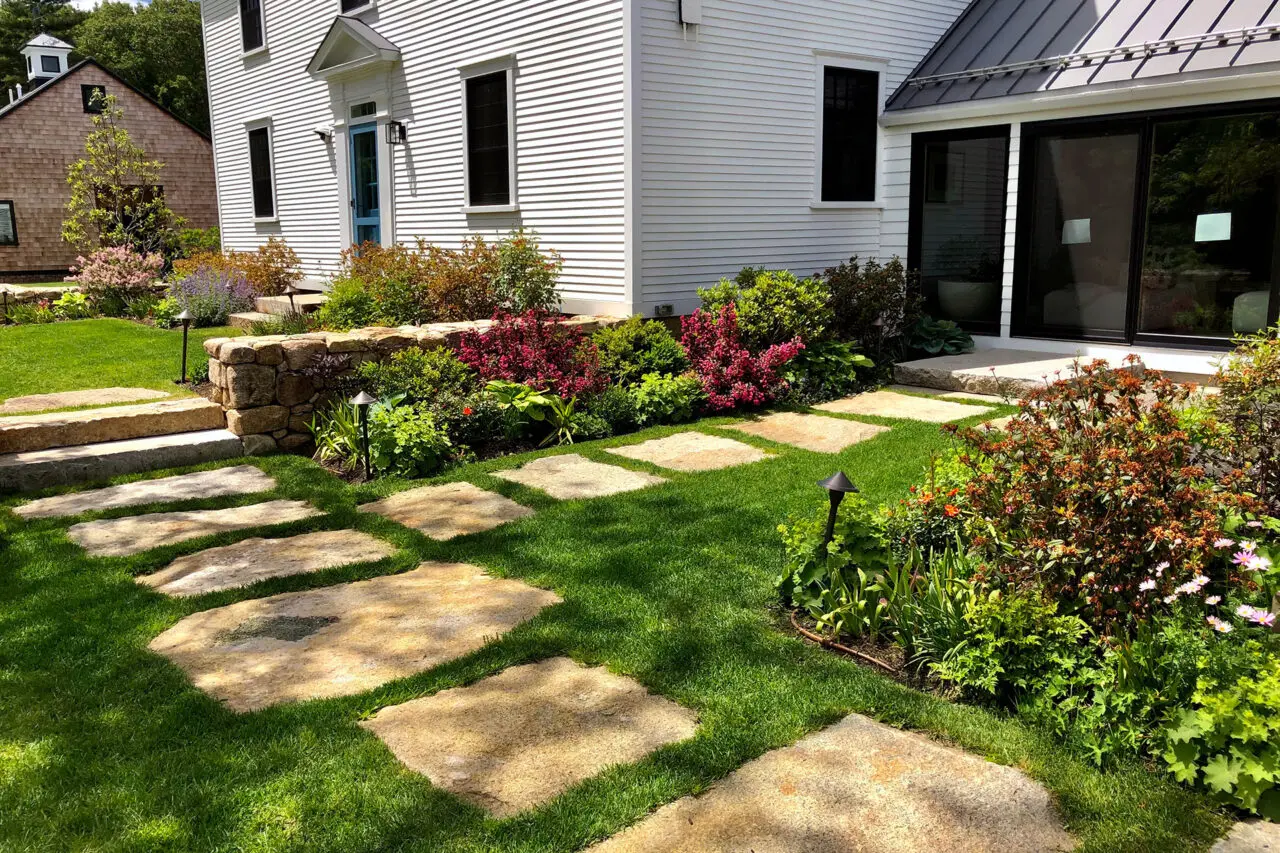 Granite stepping stones create a durable lawn path that supports casual garden circulation without overwhelming the landscape.