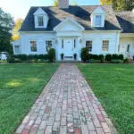 Straight reclaimed brick walkway delivers timeless curb appeal, guiding guests cleanly to the front door with warmth and New England character.