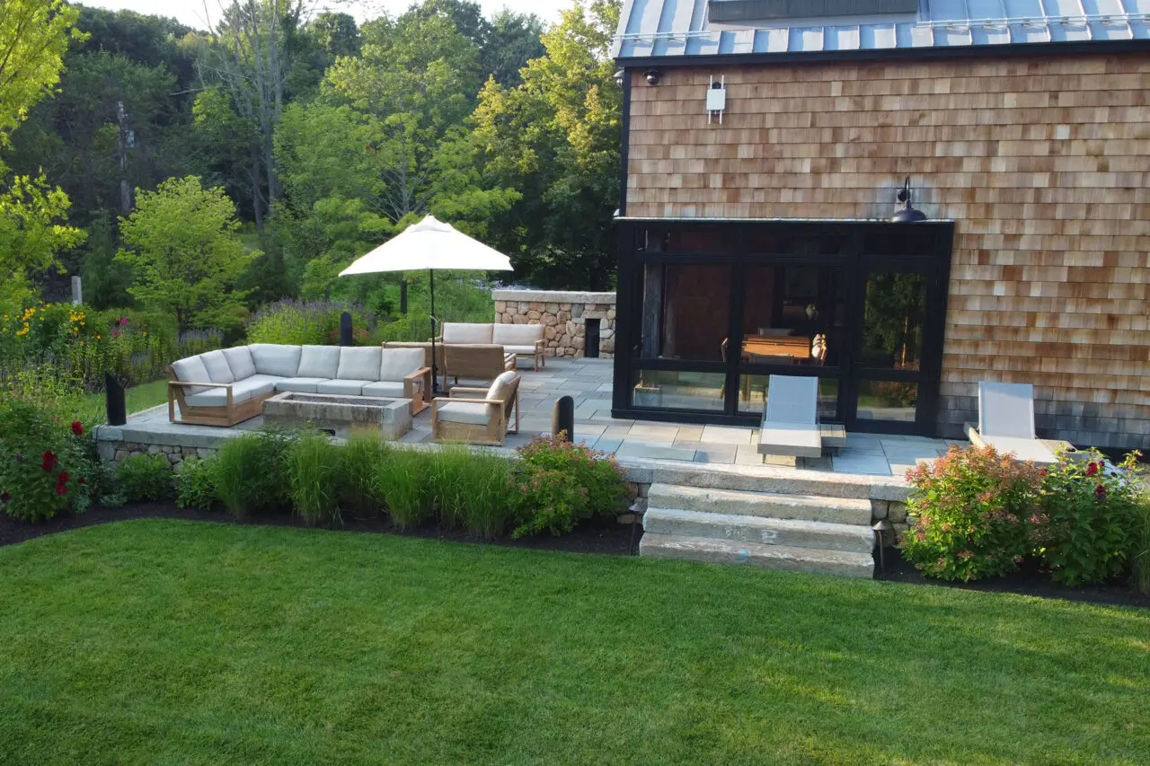 Outdoor lounge terrace with firepit set within a stone surround invites cozy evenings and social gatherings in Newburyport’s scenic outdoor settings.