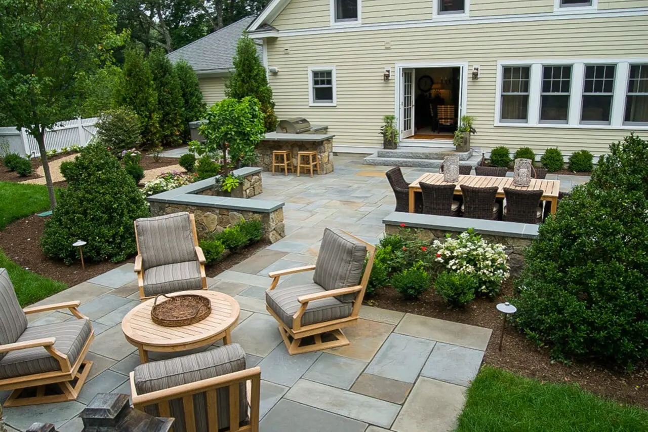 Spacious tiered patio with outdoor kitchen and lounge seating defines this backyard living area, ideal for entertaining and family meals outdoors.