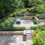 Multi‑level terrace with stone walls and a secluded seating nook blends natural texture and thoughtful layout for cozy relaxation amid lush plantings.