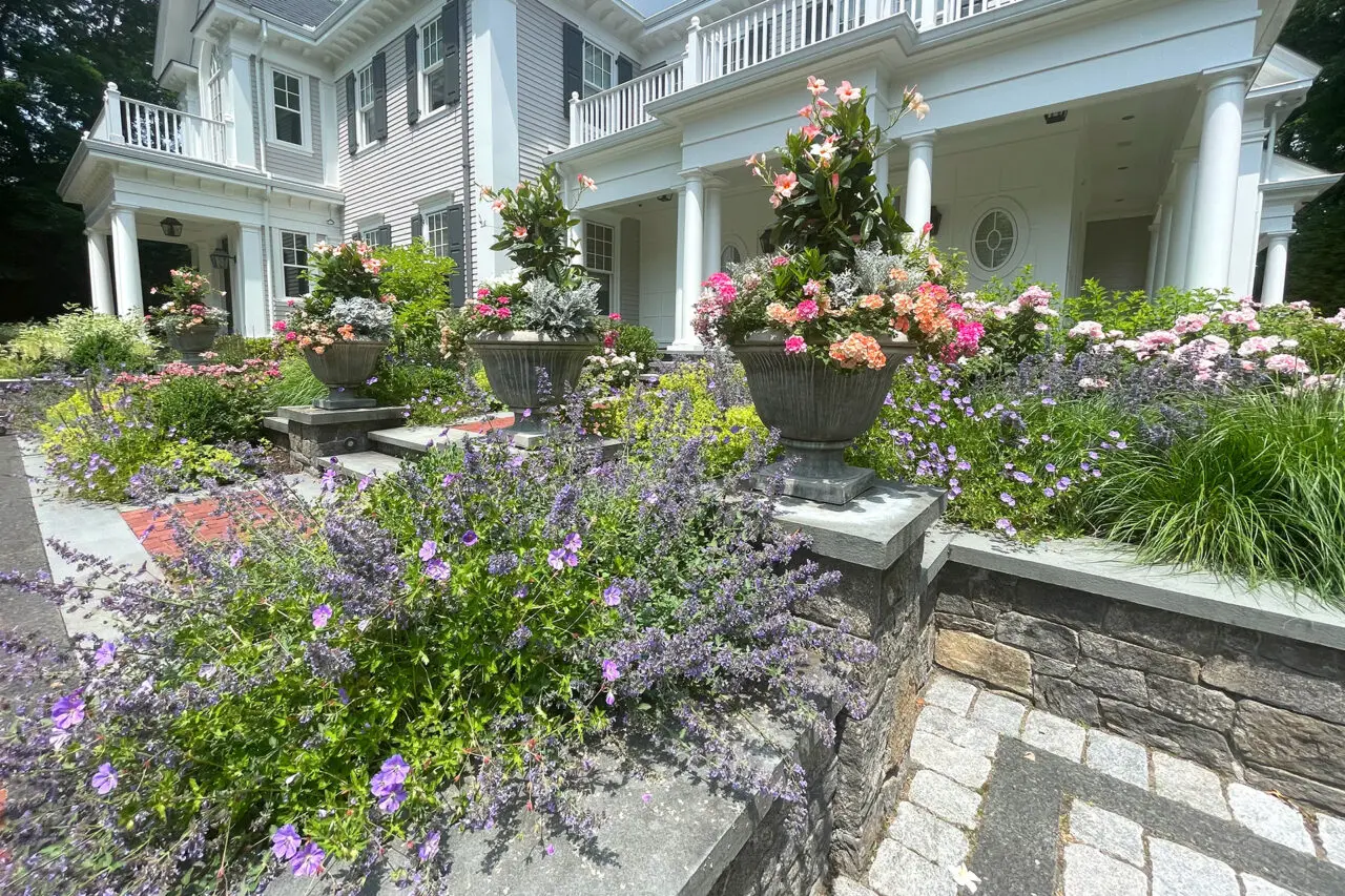 Grand stone urns filled with mixed annuals reinforce the formality of a summer garden while making seasonal color changes straightforward.