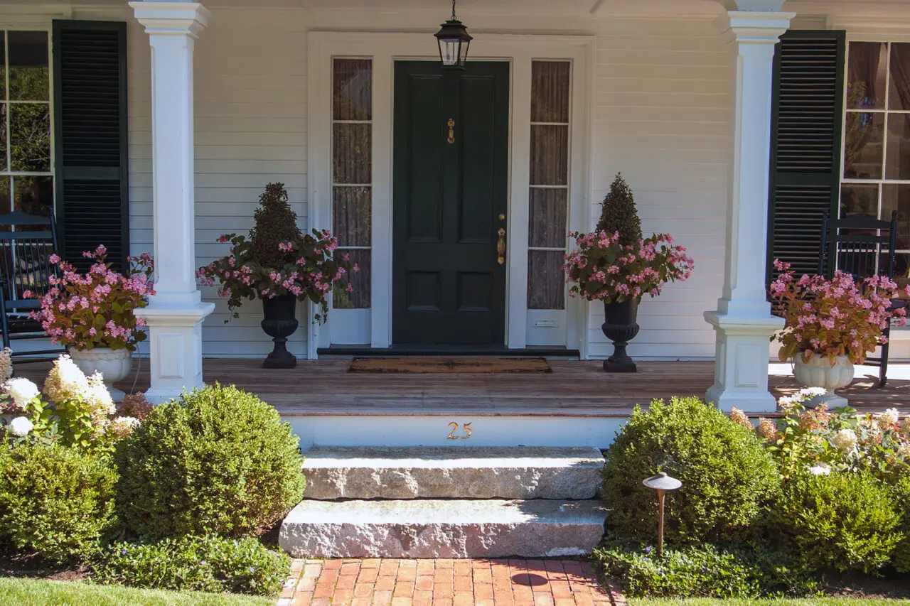Paired porch urns filled with flowering annuals create symmetry at the entry, guiding movement to the door and allowing easy seasonal color updates.