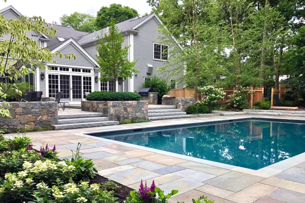 This modern rectangular pool features cut stone walls and crisp edges, using strong geometry and minimal detailing to complement contemporary architecture in Newton.
