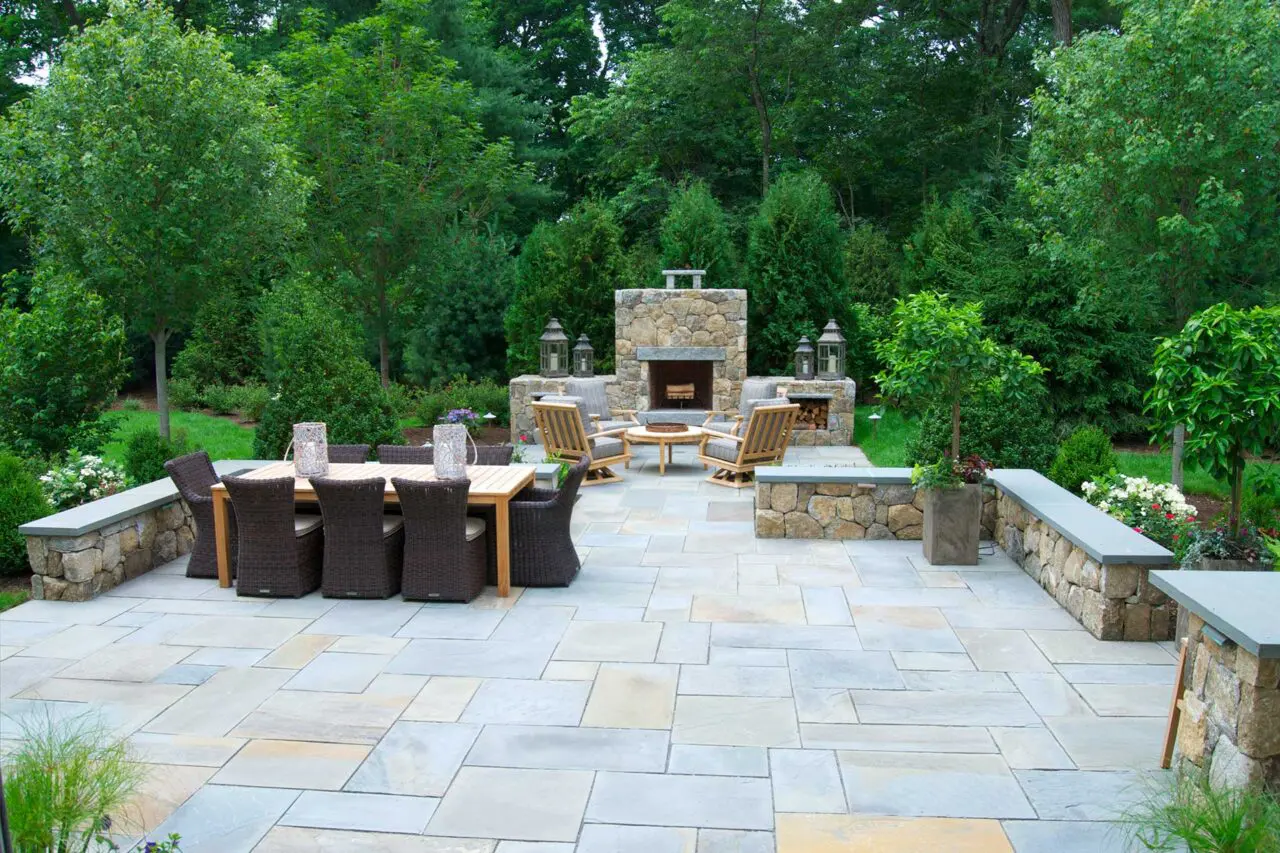 Evergreen plantings paired with masonry elements enclose this fireplace area, creating privacy and shelter for outdoor gatherings.