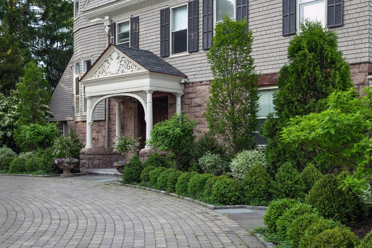 Mixed foundation shrubs surround this historic Brookline, MA entry, balancing evergreen mass with varied textures to complement architecture and create a welcoming approach.