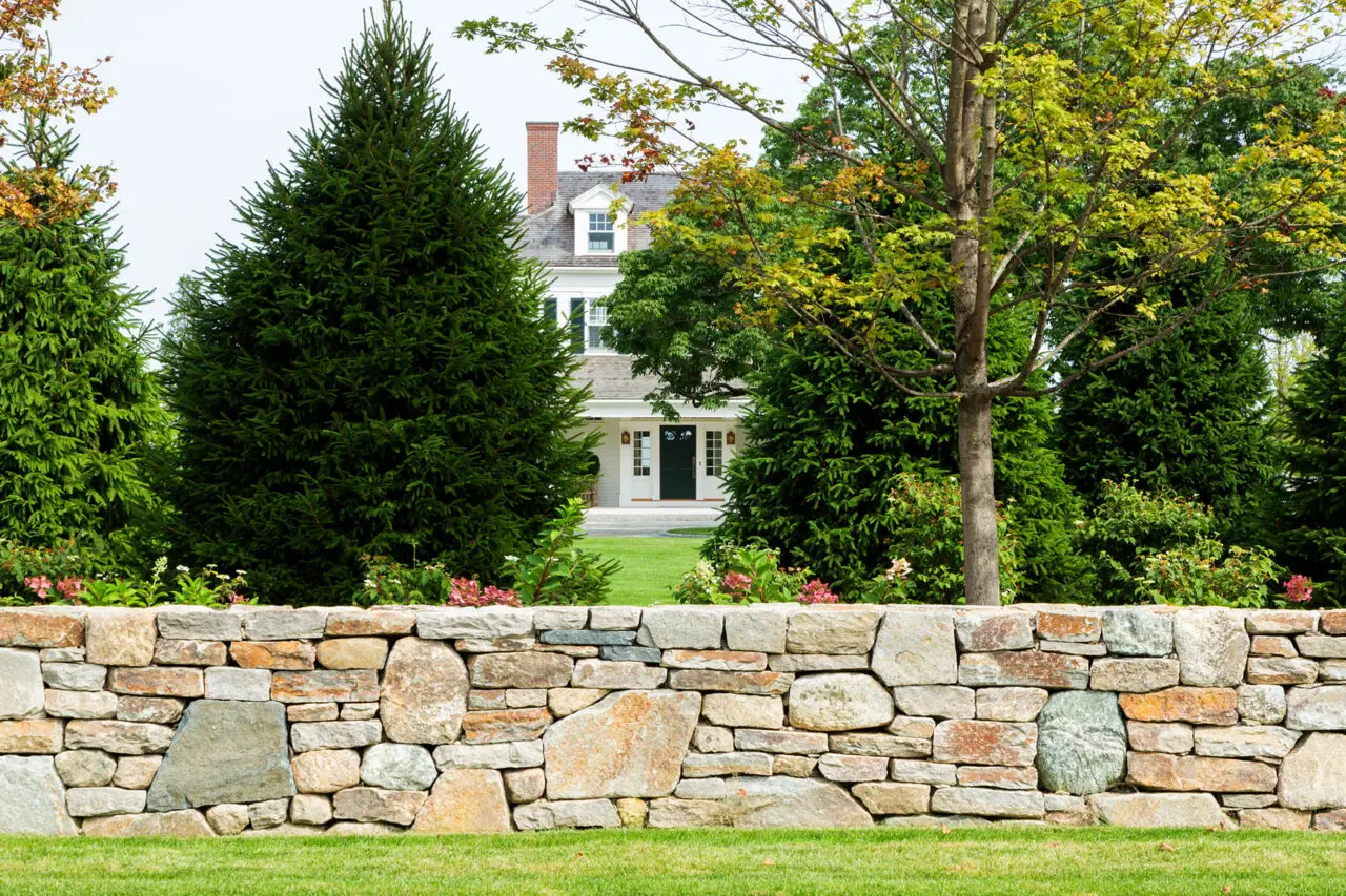 This formal front garden features a cut stone wall with crisp courses and refined proportions, framing the entry sequence while managing grade changes and reinforcing the estate’s classic architectural character.