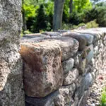 A fieldstone retaining wall manages the hillside grade, with granite steps providing a durable and clearly defined path through the slope.