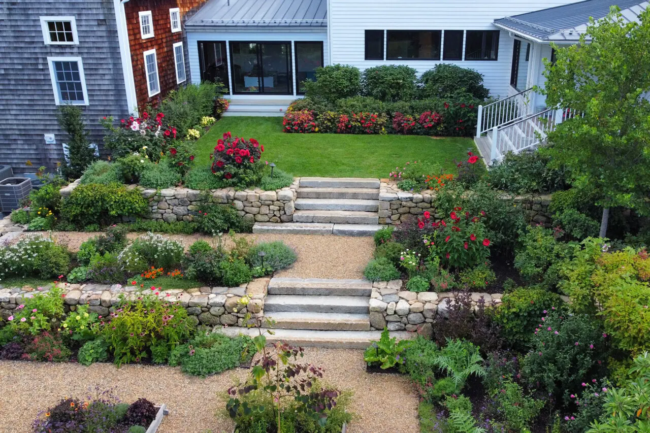 Fieldstone walls and granite steps step through a tiered garden, using shrubs and hedges to visually connect each level and create continuity.