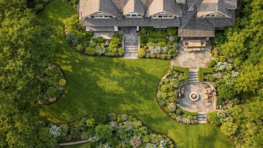 Aerial view of a lush New England estate landscape with layered planting, stone terraces, and timeless outdoor structure.
