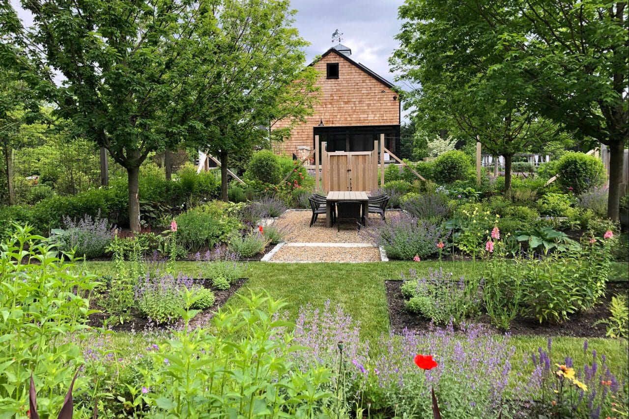 A garden setting with native plantings surrounding a simple barn structure, creating a functional outdoor space that blends naturally with its surroundings.