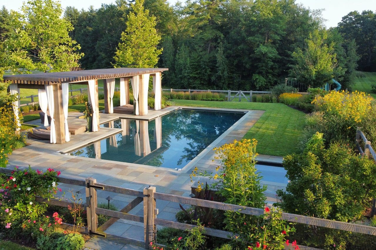 A poolside landscape with layered plantings and natural materials, designed to create a relaxed, sustainable outdoor environment that blends seamlessly with the surroundings.