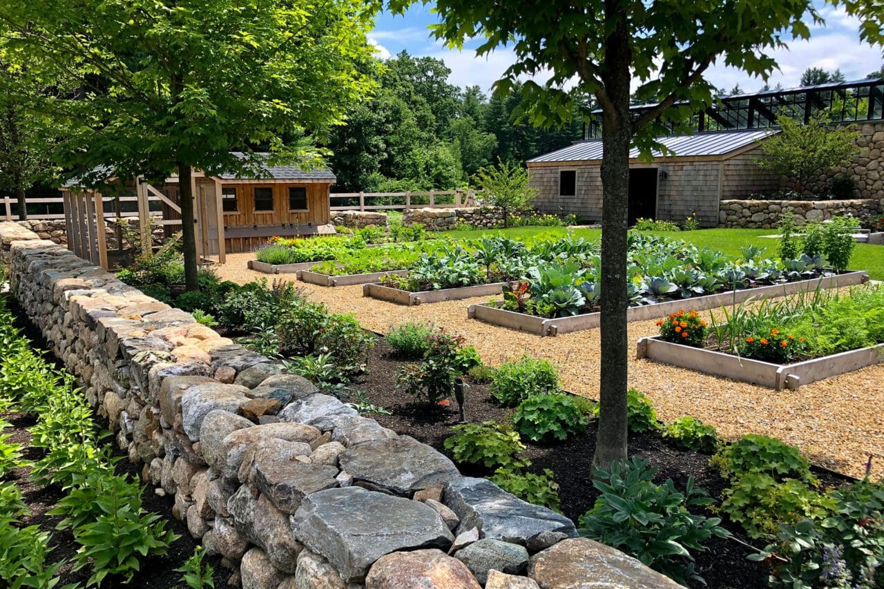 A sustainable garden with raised vegetable beds, native plantings, and stone walls that blend function, beauty, and natural materials.