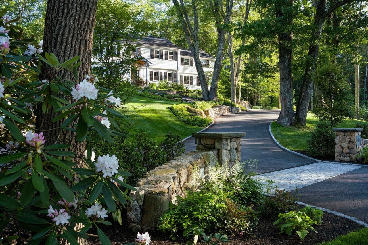 The driveway, stonework, and layered plantings are carefully aligned with the home’s architecture, creating a cohesive approach that unifies the landscape and the residence into a single, intentional design.