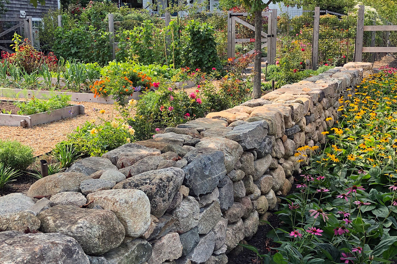 Native plantings soften a stone garden wall, supporting biodiversity while maintaining a refined, estate-appropriate aesthetic.