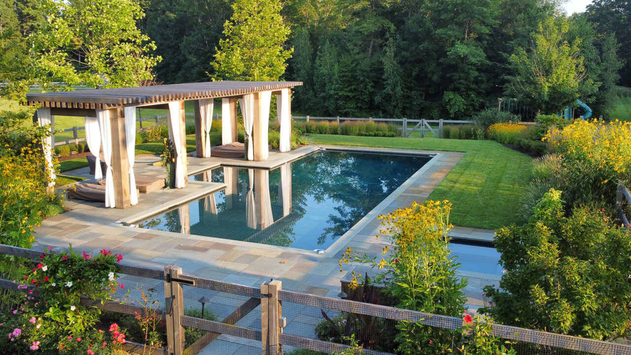 The pool terrace transitions toward open meadow plantings, balancing refined outdoor living with the surrounding rural landscape. Photo: Michael J. Lee