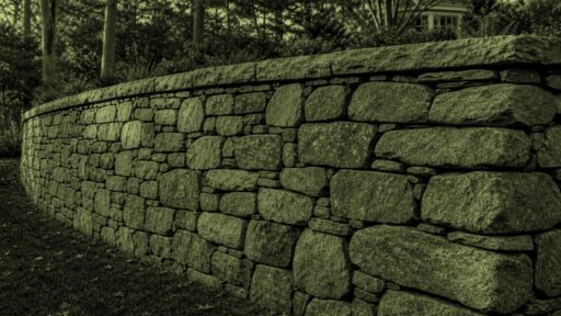 Acton, MA - A stone retaining wall leans outward, indicating movement and possible structural failure.
